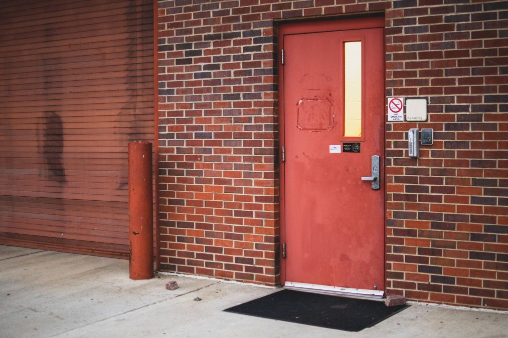a-red-industrial-entrance-door-on-a-brick-wall-exterior-with-security-access-panel-and-no-smoking-sign-stock-1790441443-1 | Flatirons Locksmiths